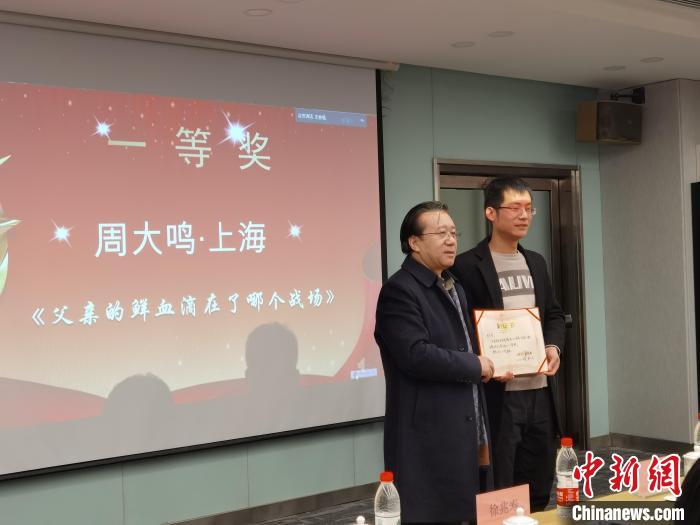 圖為作家、西北師范大學(xué)新聞與傳媒學(xué)院院長(zhǎng)徐兆壽頒發(fā)一等獎(jiǎng)證書，代領(lǐng)獎(jiǎng)?wù)呱吓_(tái)領(lǐng)獎(jiǎng)。　楊娜 攝