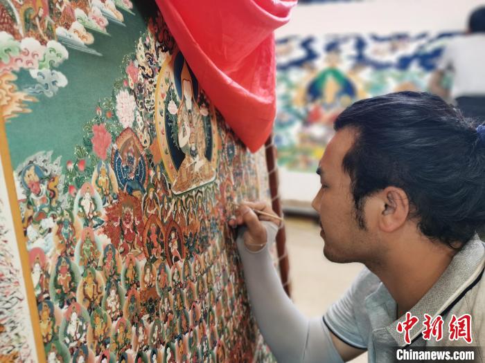 圖為更登才讓的徒弟繪畫唐卡?！?zhí)砀?攝