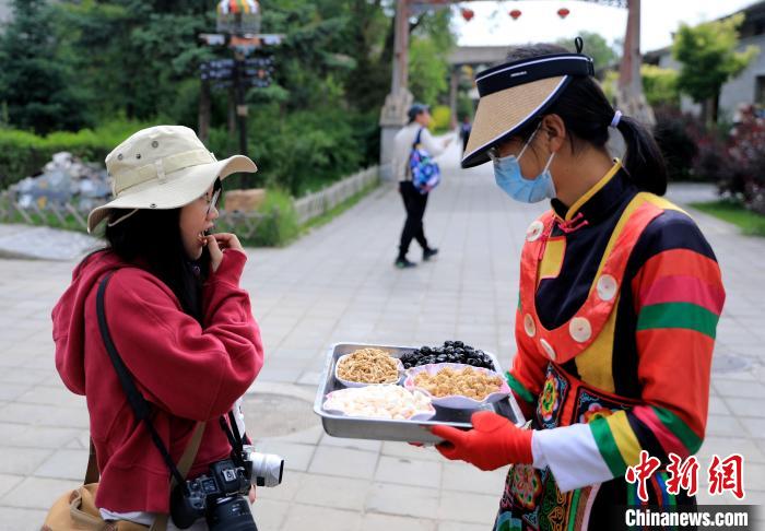 圖為身穿土族服飾的女性介紹當(dāng)?shù)靥厣〕??！⊙Φ?攝