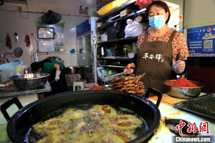 圖為平安驛·河湟民俗文化體驗(yàn)地內(nèi)的商戶炸干板魚。　薛蒂 攝
