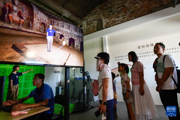 7月22日，游客體驗(yàn)“尋境敦煌——數(shù)字敦煌沉浸展”后，在虛擬演播廳拍攝一段真人與洞窟虛擬場景交互的視頻。新華社記者 郎兵兵 攝</p>
<p>