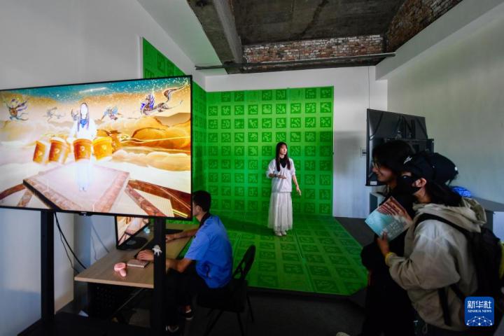 7月22日，游客體驗(yàn)“尋境敦煌——數(shù)字敦煌沉浸展”后，在虛擬演播廳拍攝一段真人與洞窟虛擬場景交互的視頻。新華社記者 郎兵兵 攝</p>
<p>